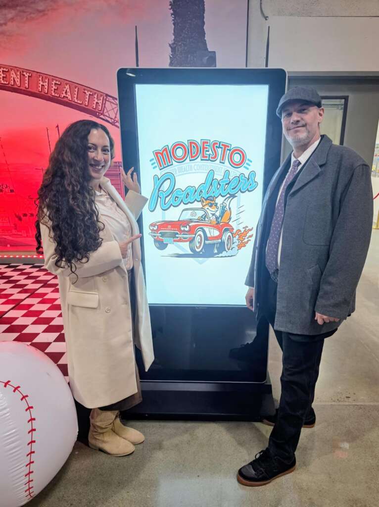 The Modesto Roadsters primary logo on a digital display at the reveal, Cruiser at the wheel of a red roadster