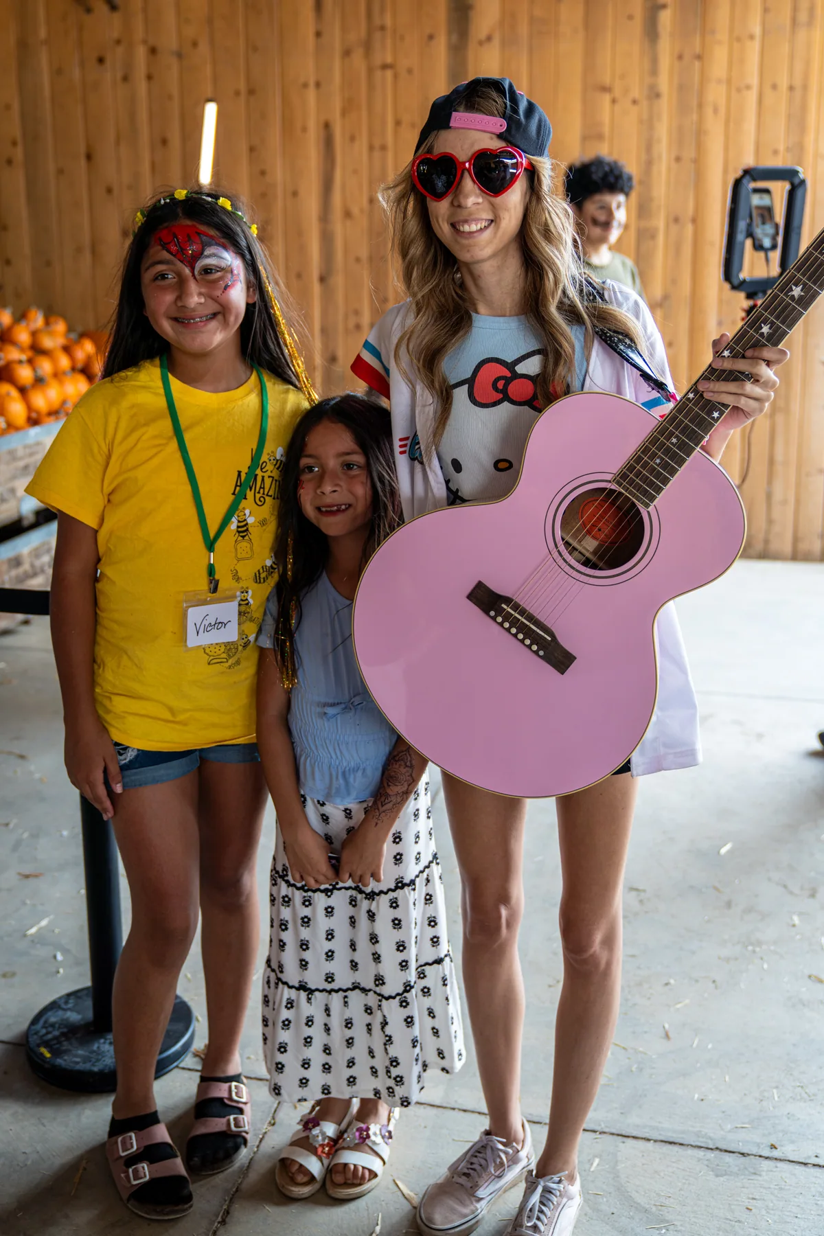 Halee Smith with her pink guitar, standing with two children at the edge of the crowd