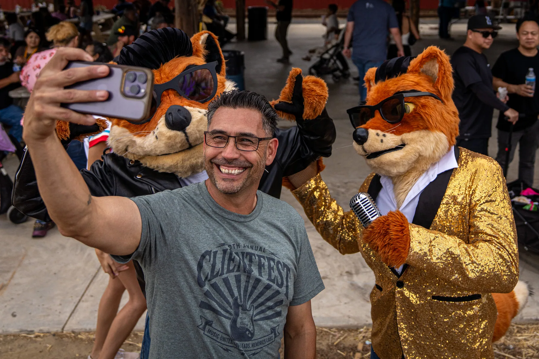 Eddie Sanchez in a ClientFest shirt holding his phone out for a selfie with Cruiser and Crooner