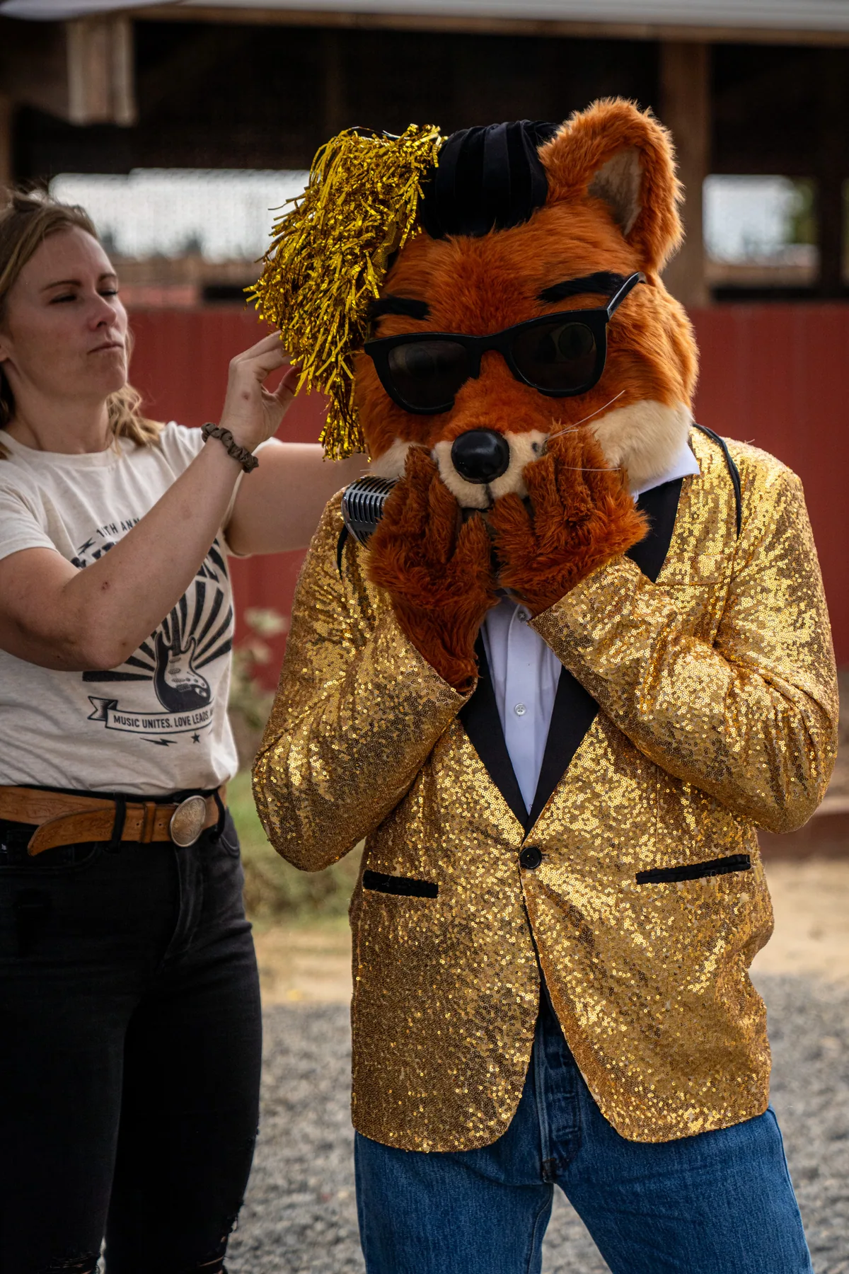A woman reaching up on tiptoe to straighten the gold tinsel on Crooner's head
