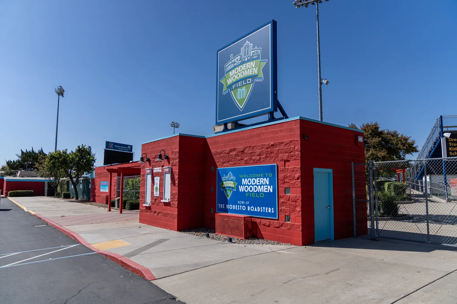 The ticket booth on the street side in mid-morning light, the Modern Woodmen Field sign above the red block wall.