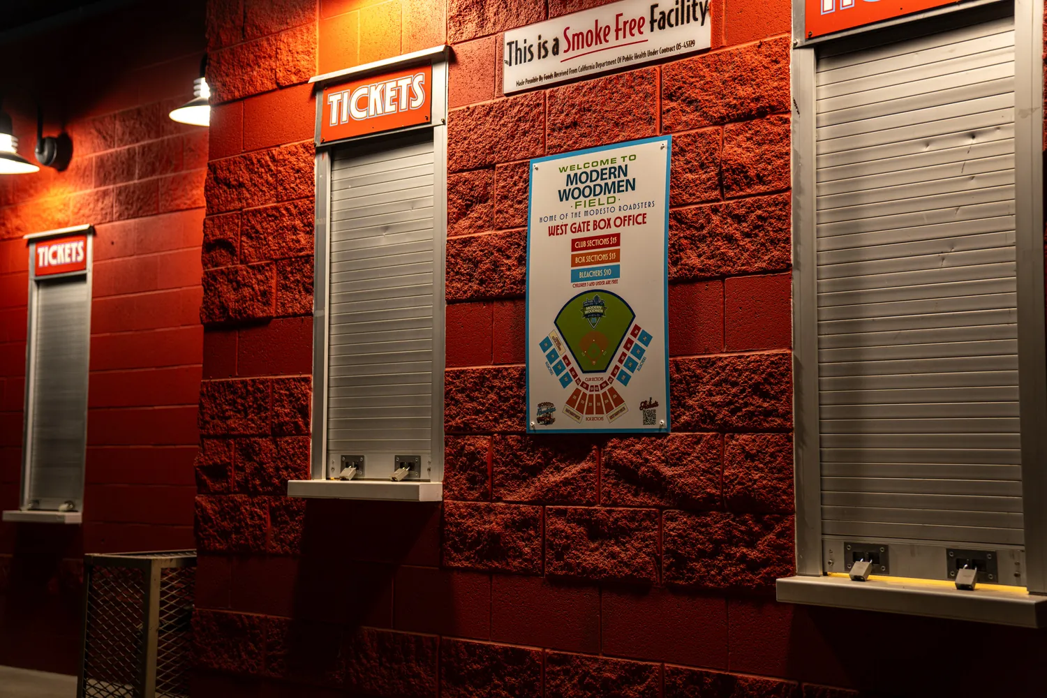 The ticket windows lit against the red block wall.