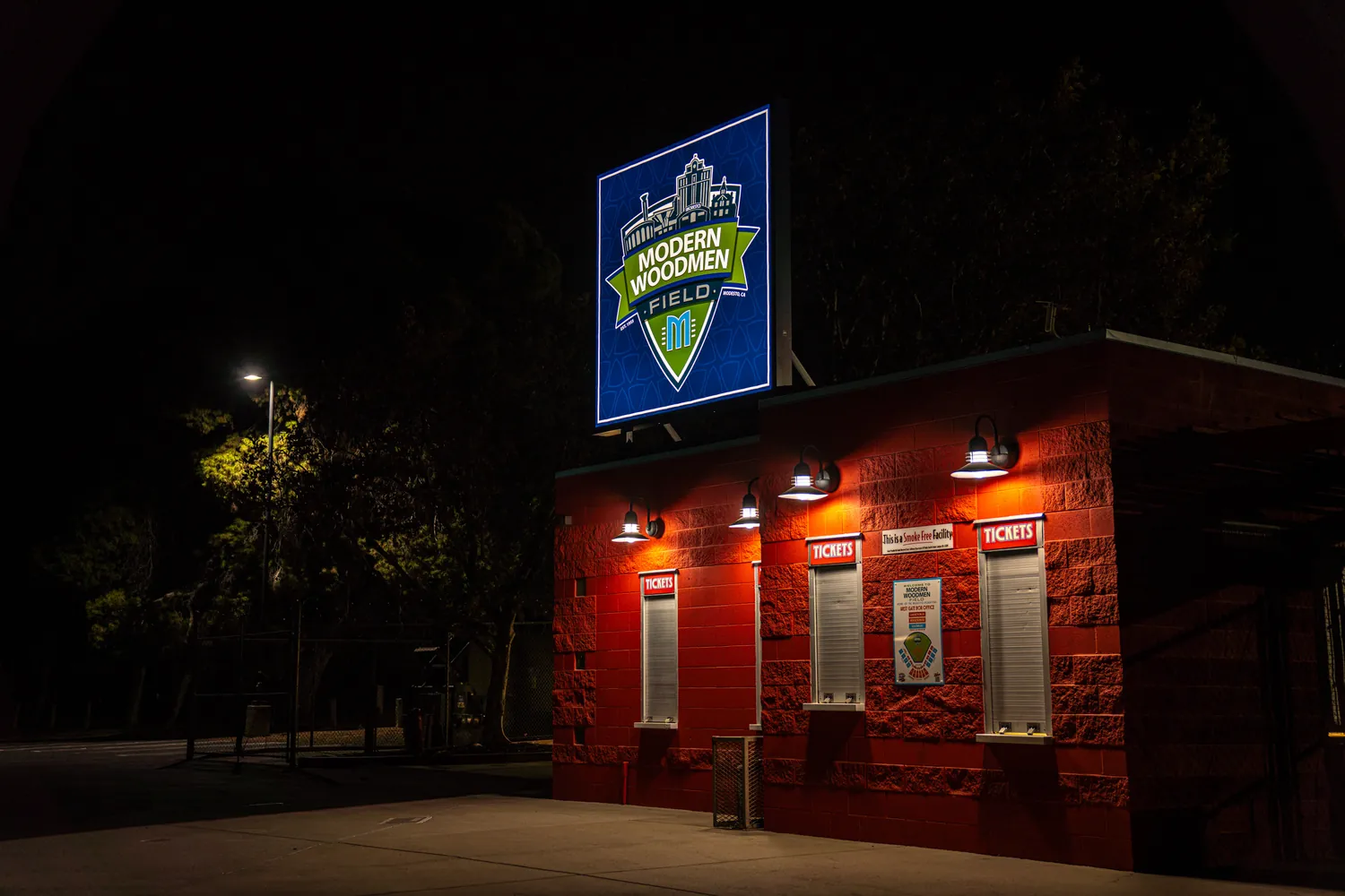 The ticket booth at night, the sign glowing over the entry.